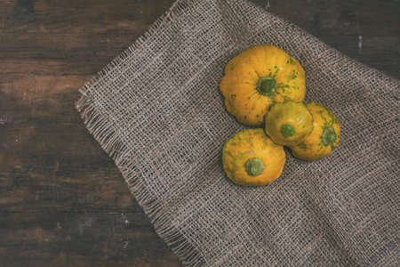 Yellow-spotted pattypan squash on a sackcloth. Dark wooden background. Copy space. Top viewの写真素材