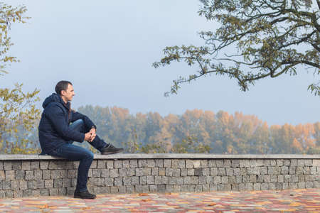 Handsome man relaxing in the autumn parkの写真素材
