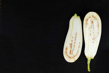 White hite eggplant on a black stone surface. The half eggplant. Top view. Copy space.の写真素材
