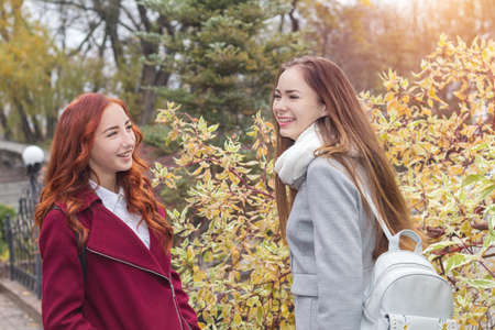 Two happy young girls at bright autumn backgroundの写真素材