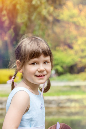 Cute little girl plaing in the city park on a summer sunny day. Portrait little girl close up, big...