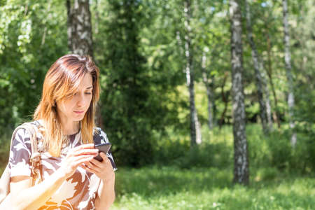 Young redhead woman using the phone outdoors on a sunny day.  Portrait redhead woman on the phone with copy spaceの写真素材