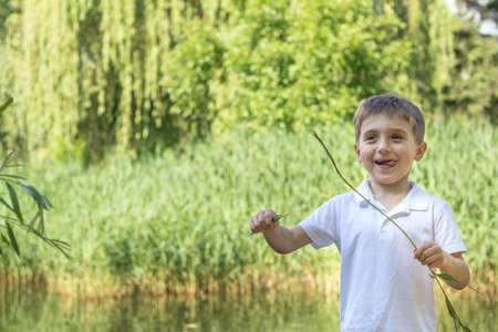  Happy little boy playing at the pond in the city park on a summer sunny day. Close up. Beautiful summer background with copy spaceの写真素材