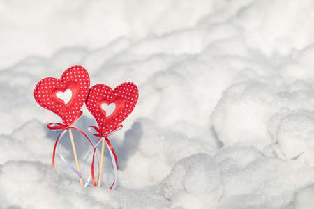 Beautiful valentine holiday background with two checkered hearts on cane, white snow surface.の写真素材