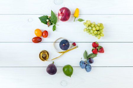 Fitness healthy food on white wooden background (lime, strawberry, plum, figs, raspberries, grapes,...