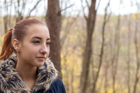 Cute beautiful pretty redhead female teenager in autumn forest. Close up charming portrait, shallow depth of field, toned.の写真素材