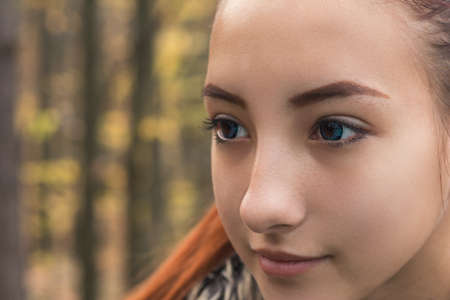 Cute beautiful pretty redhead female teenager in autumn forest. Close up charming portrait, shallow depth of field, toned.の写真素材