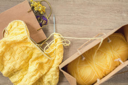 Light yellow knitting wool and knitting needles on wooden background. Top view.copy space. Knitted fabric and yarn on a wooden surface.の写真素材