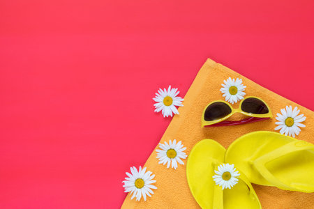 Summer yellow accessories with chamomile flowers on pink floor. Top view and copy space,...