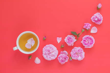 Cup of tea with pink roses flower bouquet on pink red backgroundの写真素材