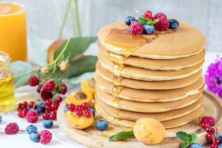 Fresh delicious pancakes with summer raspberries, blueberries, red currants, apricot, peach and...
