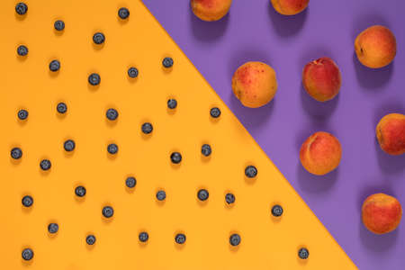 Many juicy beautiful amazing nice peaches and blueberries on violet and yellow surface. Beautiful food art background. Top view, copy space.の写真素材