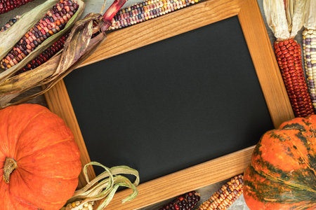 Holiday Halloween background with indian multicolored corn, pumpkin and slate blackboard, top view.の写真素材