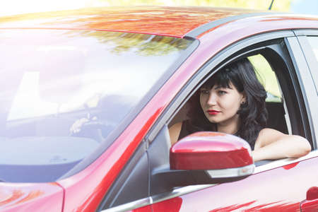 Sexy beautiful pretty brunette with red lipstick in the red car. Selective focus, shallow depth of the field.の写真素材