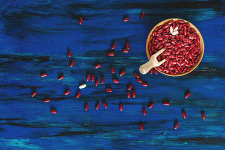 Red kidney beans in wooden dish on dark blue wooden background top view.の写真素材