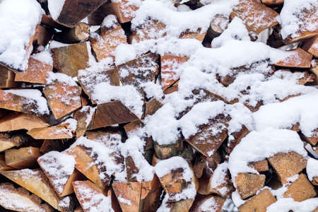 Winter background texture pattern with stacked dry chopped firewood logs covered with snow. Firewood patternの写真素材