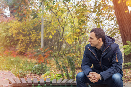 Handsome man walking in the autumn park, nice sunny day in the city.
