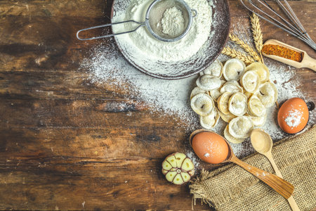 Raw homemade delicious traditional italian ravioli, dumplings with meat and set ingredients on dark wooden old surface, top view, copy space.の写真素材