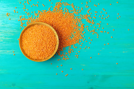 Red lentils in wood plate on on a blue turquoise wooden table background. Top view, copy space.の写真素材