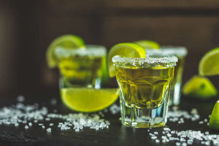 Mexican Gold Tequila shot  with lime and salt on black stone table surface, selective focus, shallow depth of the field, copy space.の写真素材