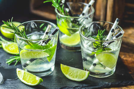 Fresh cocktail with lime, ice and rosemary, mojito cocktail in a bur on a rustic table, selective focus, shallow depth of the field.の写真素材