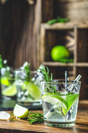 Fresh cocktail with lime, ice and rosemary, mojito cocktail in a bur on a rustic table, selective focus, shallow depth of the field.の写真素材