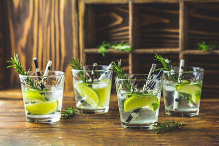 Fresh cocktail with lime, ice and rosemary, mojito cocktail in a bur on a rustic table, selective focus, shallow depth of the field.の写真素材
