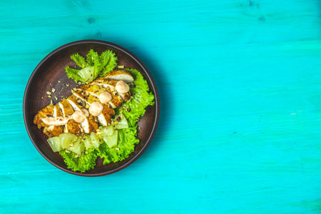 Delicious salad, chicken with pineapple, lettuce, cream sauce and walnut in ceramic plate on a blue...