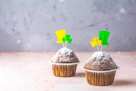Tasty delicious homemade muffin on light pink living coral stone concrete surface with knitting hearts, copy space. Sweet food for Saint Patrick day.の写真素材