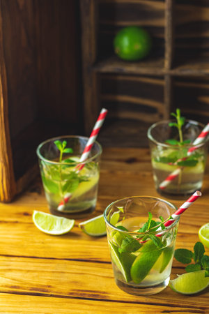 Fresh alcoholic cocktail with lime, ice and mint, mojito cocktail in a bur on a rustic table,...