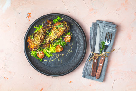 Baked chicken drumstick in a black ceramic plate with orange and rosemary, light pink living coral...