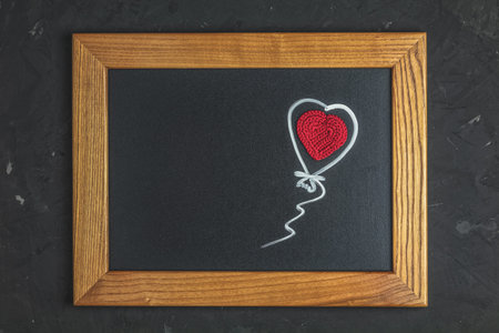 Valentines Day greeting card with red wool crochet heart on black surface in wooden frame, top view,...