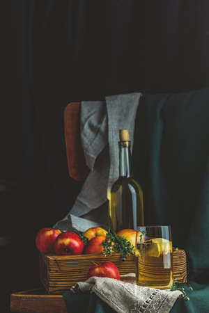 Apple cider vinegar or fruits tea with apple slices in glass with ripe red apples in box, dark vintage rustic style. Shallow depth of the field.の写真素材