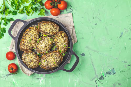 Delicious portion baked potatoes in black frying pan with pesto sauce, green onion and cheese. Dish for dinner. Top view, flat layの写真素材