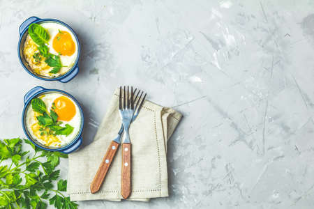 Baked eggs  in blue ceramic baking molds. Portioned casserole from vegetables and eggs in Italian or french style. Eggs kokot cocotte  breakfast. Top view, copy space for you text.の写真素材