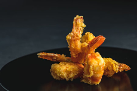 Fried Shrimps tempura in black plate on dark concrete surface background. Copy space for  text.