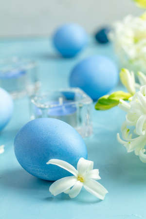 Easter eggs, candles and white hyacinth on a blue concrete background with empty copy space. Festive background, Happy Easter greeting card.の写真素材