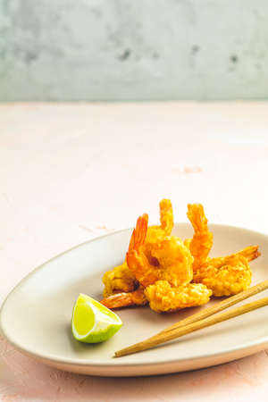 Fried Shrimps tempura in light plate on pink or peach concrete surface background. Copy space for text. Seafood tempura dish of traditional asian cuisine.の写真素材