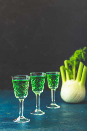 Traditional italian or czech liqueur or bitter with fennel. Three absinthe glass. Dark blue concrete table surface background, copy space for text.の写真素材