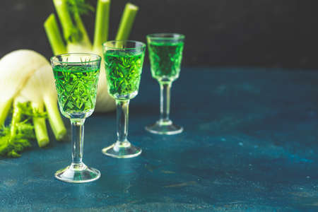 Traditional italian or czech liqueur or bitter with fennel. Three absinthe glass. Dark blue concrete table surface background, copy space for you text.の写真素材