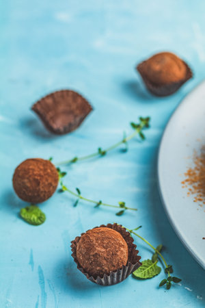 Cocoa balls, handmade chocolate balls cakes in a blue tray, sprinkled with cocoa powder, fresh mint...