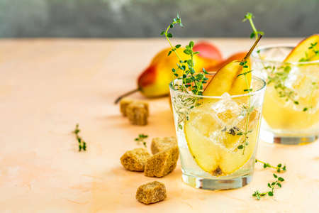 Cold pear white tea with thyme on the wooden background. Festive summer drinks, pear thyme cocktail. Selective focus, space for text.の写真素材