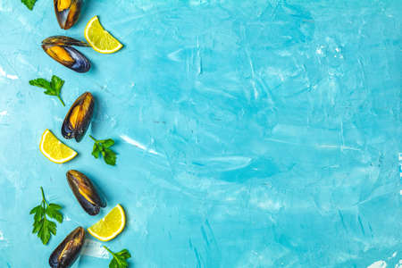 Seafood mussels with lemon and parsley on light blue concrete table surface, top view, copy space for you textの写真素材