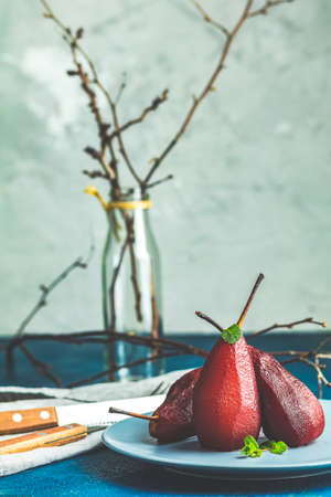 Traditional dessert pears stewed in red wine with chocolate sauce on plate on blue concrete surface. Concept for romantic dinner dessert. Simple Paleo style dessert pear poached in pomegranate juiceの写真素材
