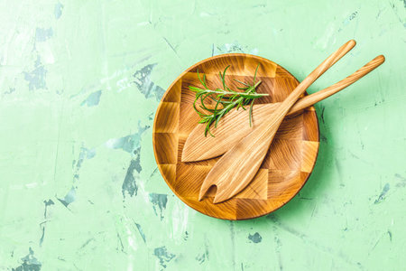 Wooden spoons for salad in wooden plate over green concrete texture background, healthy food...