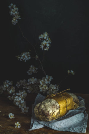 Freshly baked rye handmade breads on old wooden table with linen napkin and apricot tree blossom...