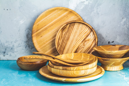 Variety of wooden bowl, wooden spoons for salad over blue texture background. Food or ecology...