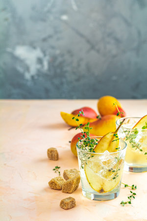 Cold pear white tea with thyme on the pink concrete table background. Festive summer drinks, pear thyme cocktail. Selective focus, space for textの写真素材