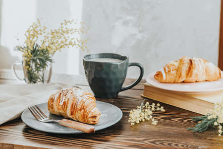 Continental traditional breakfast with croissants and coffee served on wooden table background empty copy space. French breakfast.の写真素材