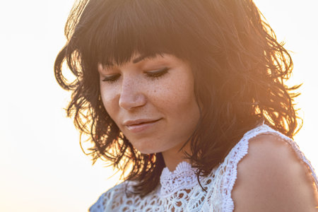 Cute happy beautiful woman female against a background of the sunset. Gold backlight. Close up. Nice...